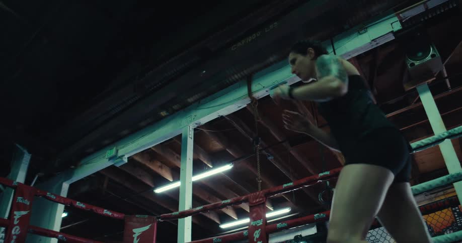 Female kick boxer trains alone in the boxing ring at the boxing gym