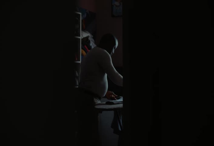 Man irons his clothes using a clothes iron and a full sized ironing board