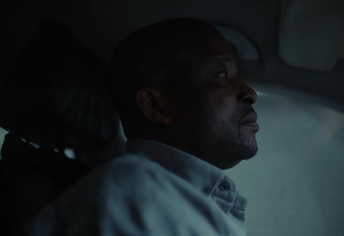 A man is driving his car through an urban city