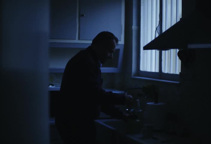 A man is washing dishes in the kitchen of his home