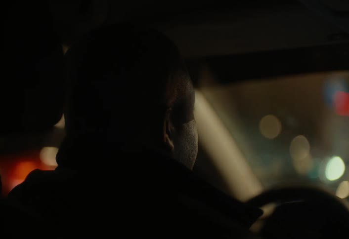 A man stops in traffic at night