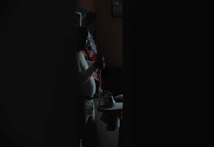 A man is ironing in the dark room