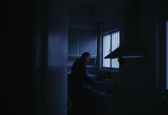 Silhouette of a man at dawn with a cup in the kitchen