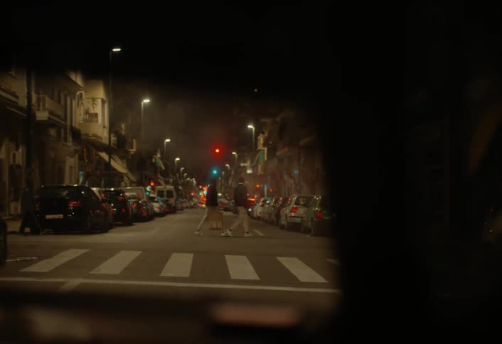 A car slows down as people cross the road