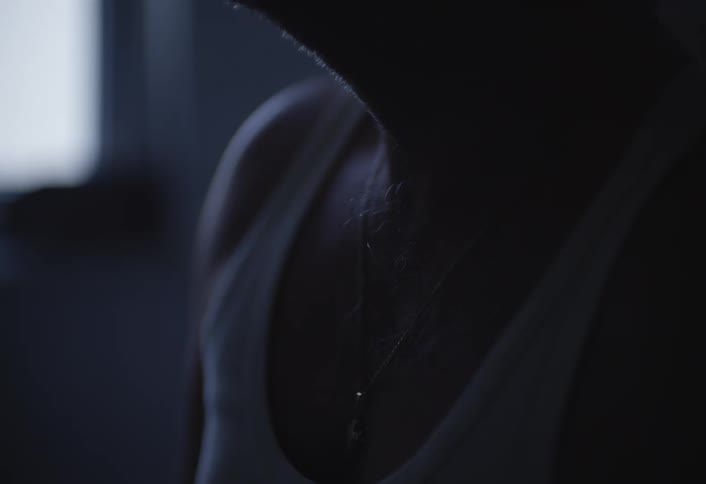 A man touches the medallion on his neck in the dark