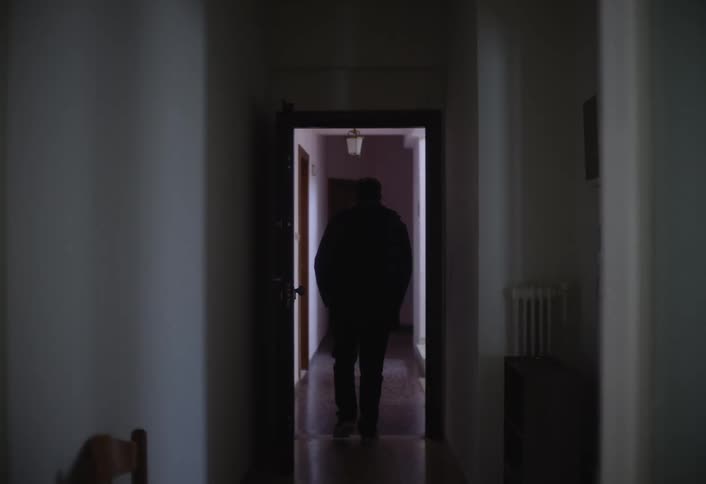 Man puts on a jacket and leaves before walking back to close his door