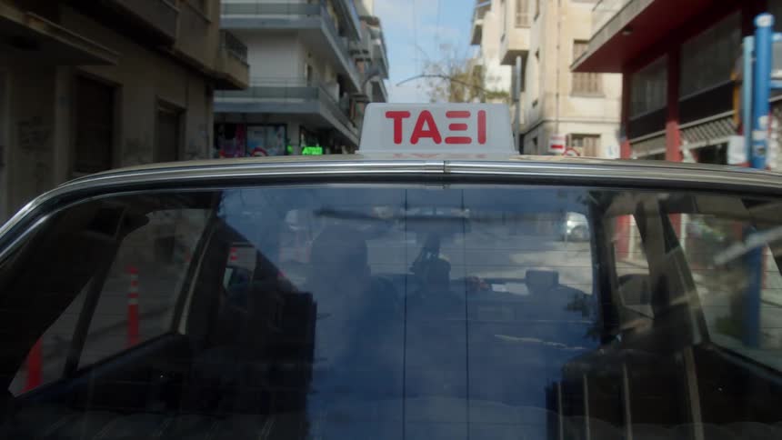 A taxi travels past the apartments