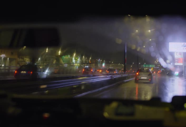 Traffic is moving in the rain at night