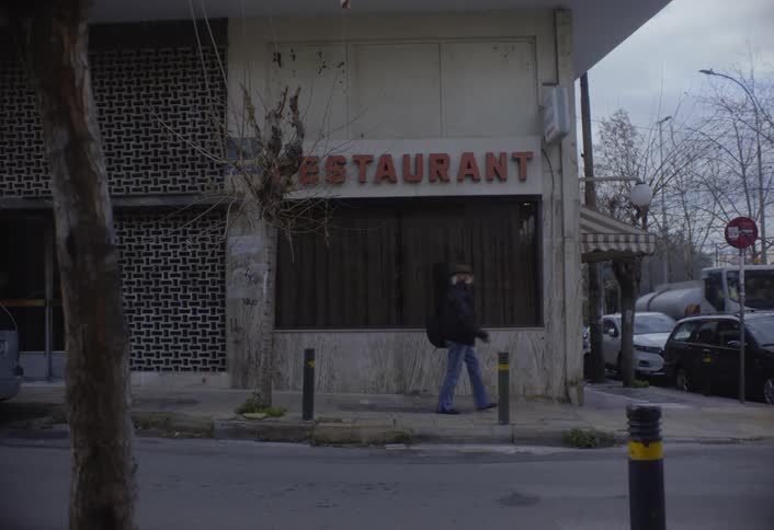 A footage of people walking the street and cars parked by the road side