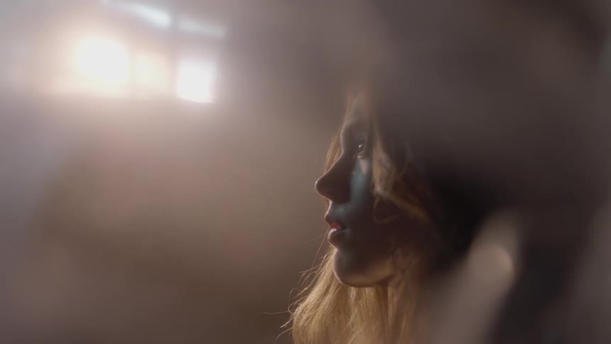 A woman looks up as sun shines through a window