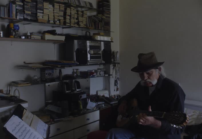 A man sits down and plays the guitar
