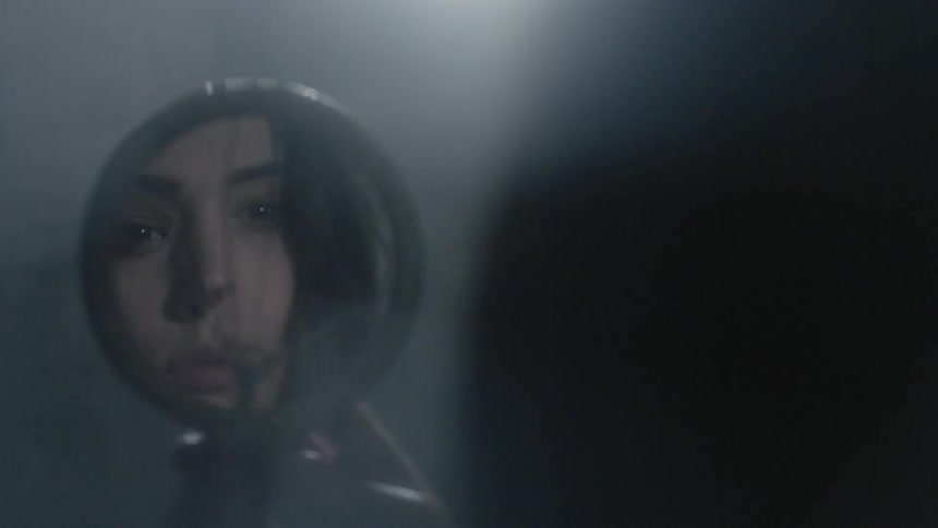 A woman looks at her reflection in a small broken mirror