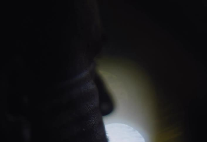 A close up of the face of a tired man rubbing his eyes while driving at night