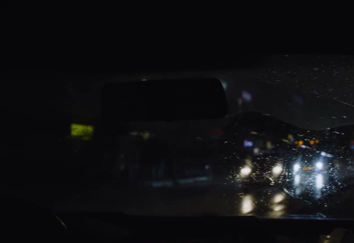 Someone is driving a vehicle through a populated city during the night