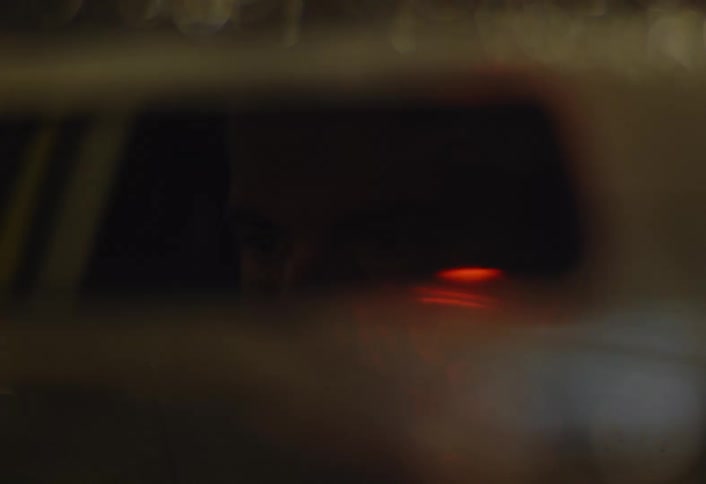 A man adjusts his rearview mirror in the rain