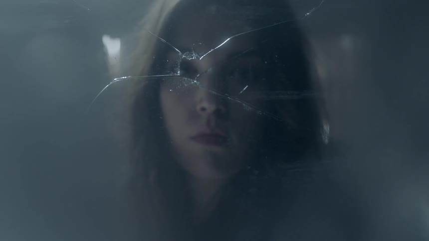 A woman staring out a broken window
