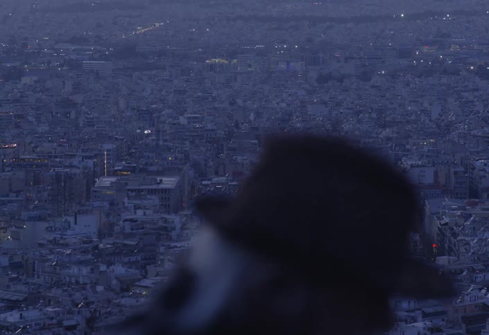 Man in foreground talking and smoking with landscape over a city