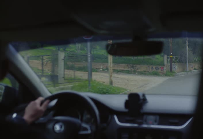 A man is driving down the neighborhood street