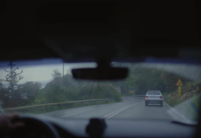 Cars drive on the winding roads as it rains