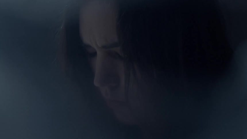 A woman is looking down in a very dark room