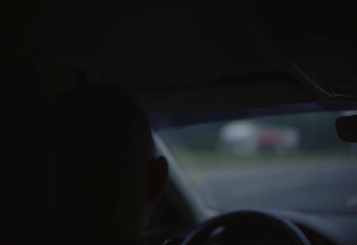 Driving on a multilane highway vehicles move ahead while roadside elements come into view under an overcast sky