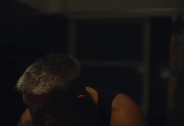 Gray haired man looks at his reflection while shaving