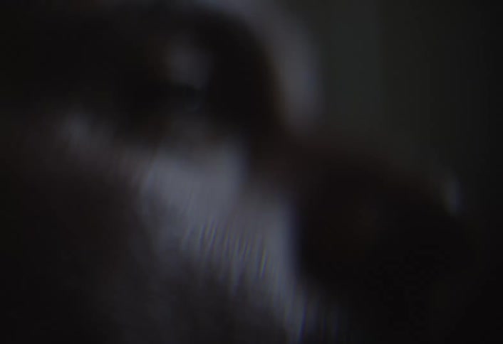 A closeup shot focuses on a face in low lighting conditions