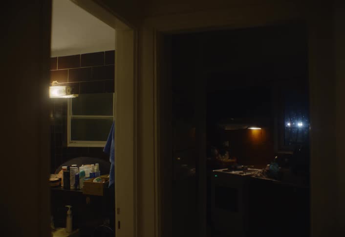 A man turns on the bathroom light during his morning routine in a dimly lit house
