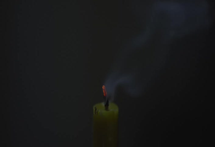 Candle burning then being blown out against a black background