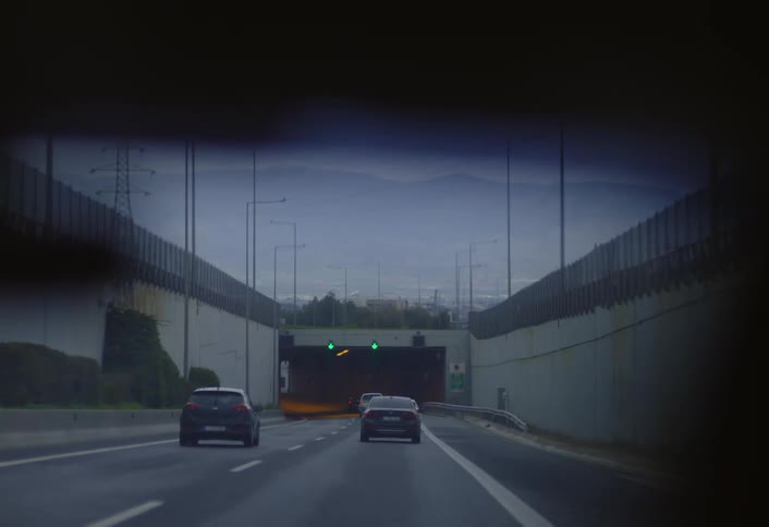 Multiple cars driving on a busy highway under a tunnel