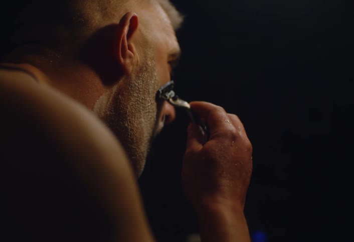 A man is shaving in a dark room