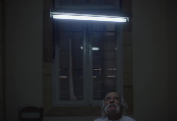 Older man smokes while sitting at home near a window