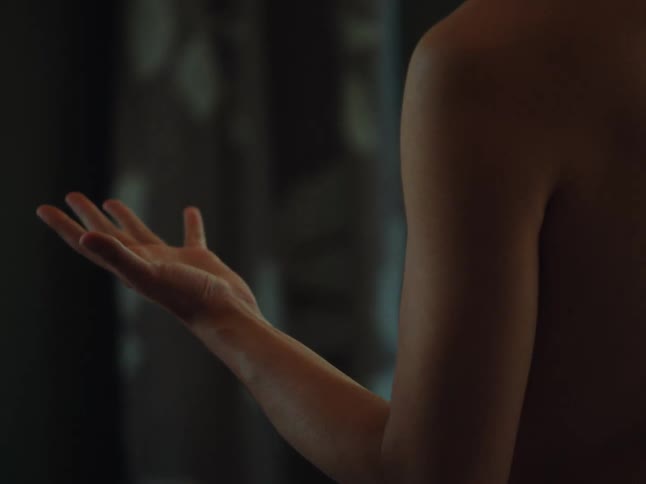Person stands topless while flexing their hand
