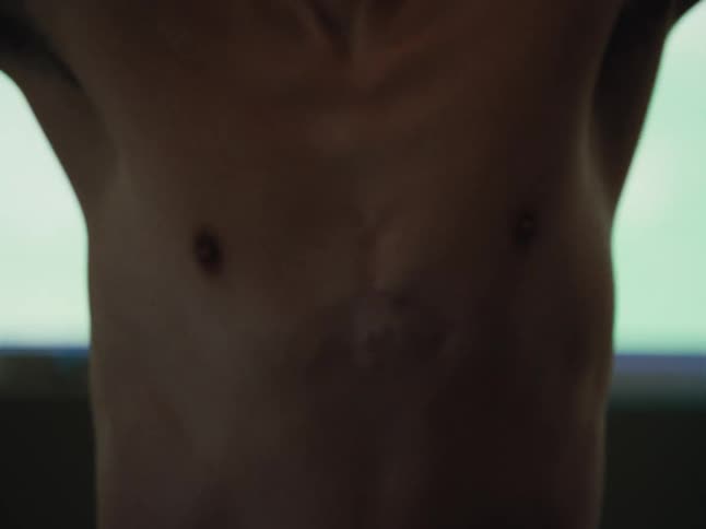 A man is stretching his arms while standing indoors