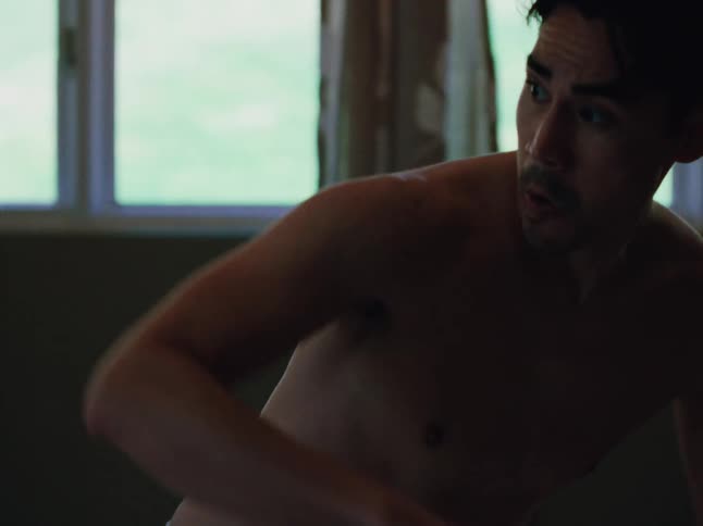 A shirtless man executes a martial arts kick twisting his torso and glancing behind him