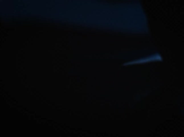 A closeup shows a partially visible dark metallic surface reflecting a warm orangetoned light source