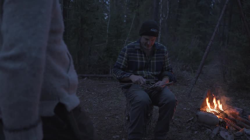 Two friends are talking and sitting by a bonfire