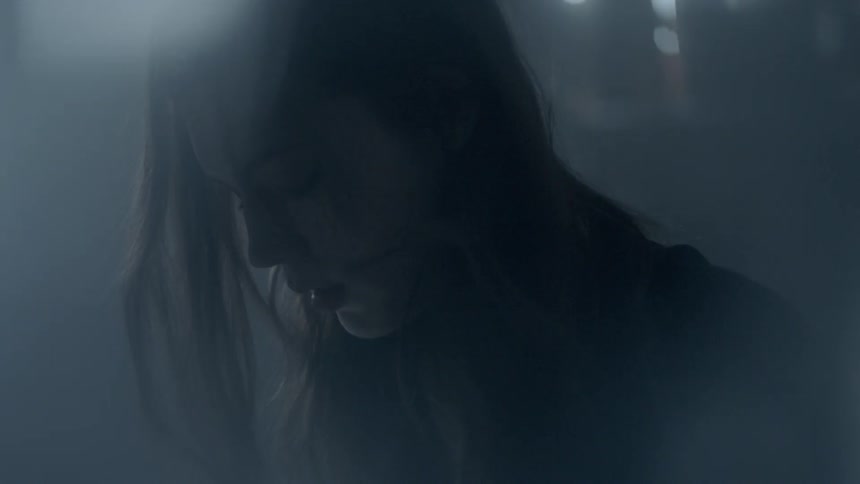 A woman is looking down in a dark room