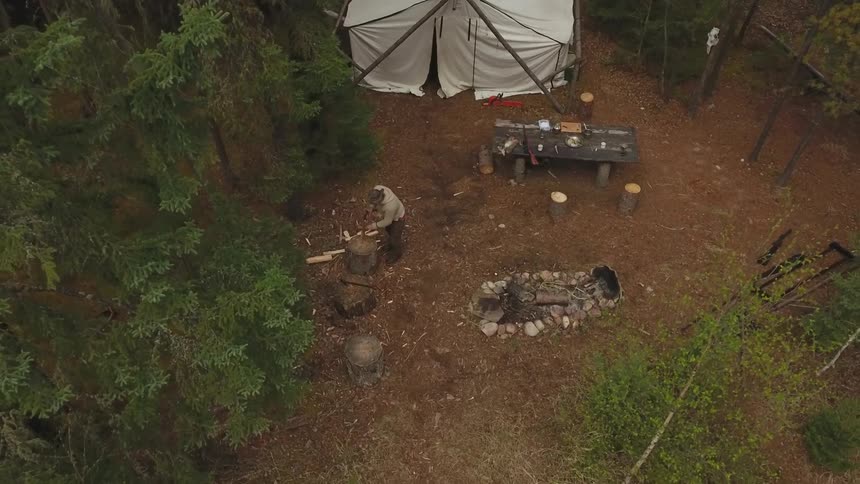 Person camping in the forest chops wood during the day