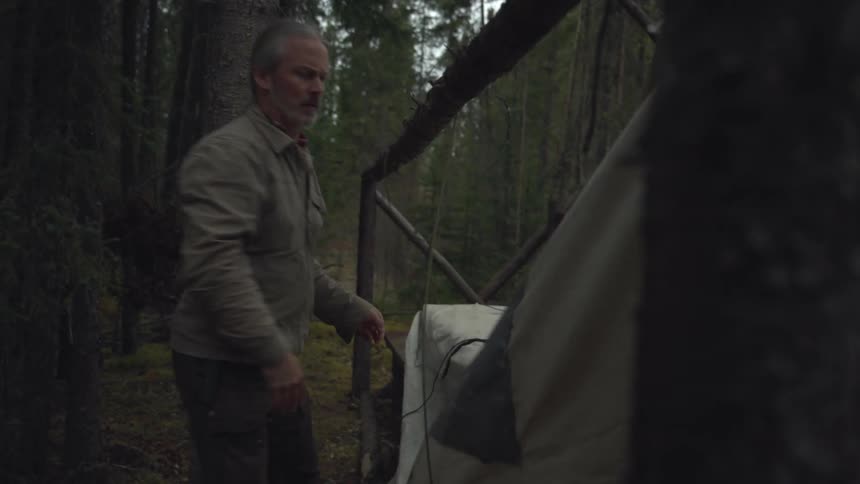 A man is setting up his tent with ropes