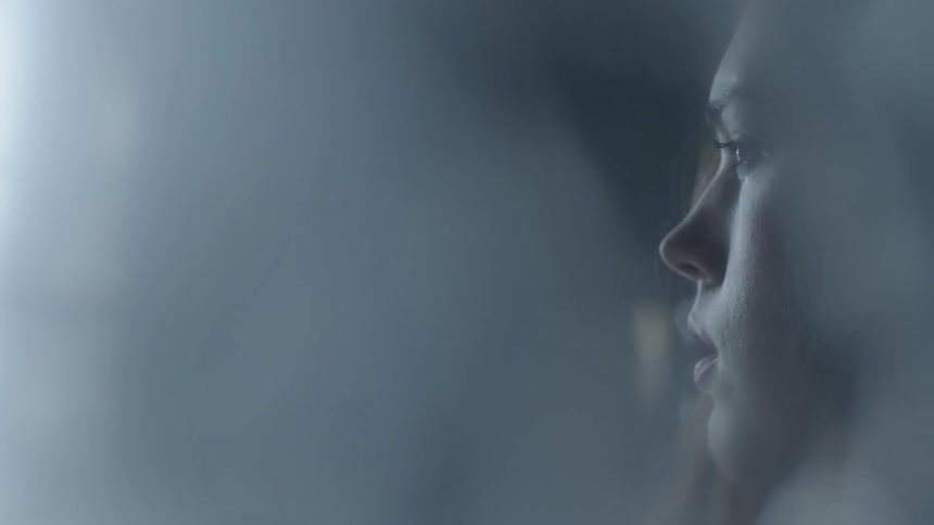 A woman looks forward in a dark room