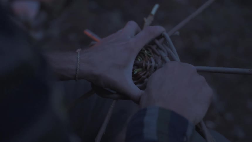 A man is making a trap with sticks