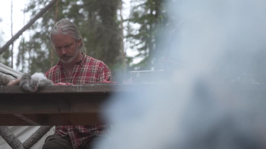 A man is skinning animals by the campfire