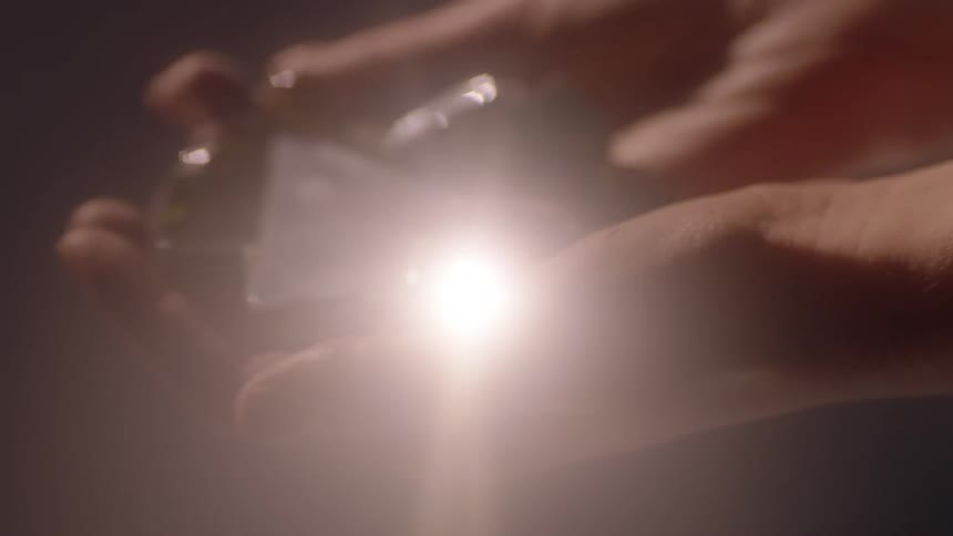 Light reflects off glass in a woman's hands