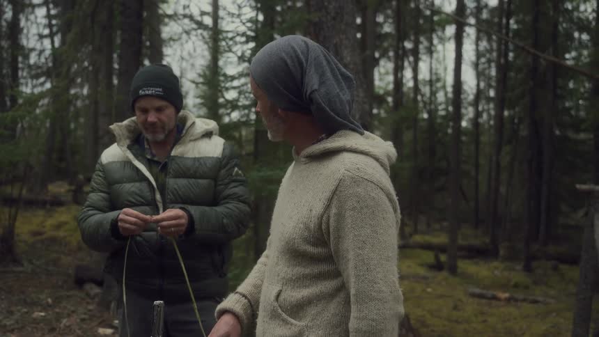 Two men are crafting something in the woods