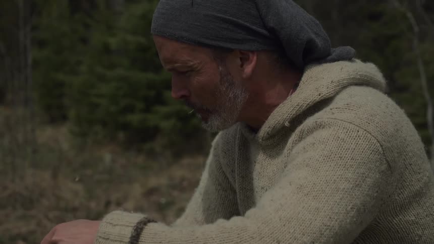 A man chews on a piece of wood