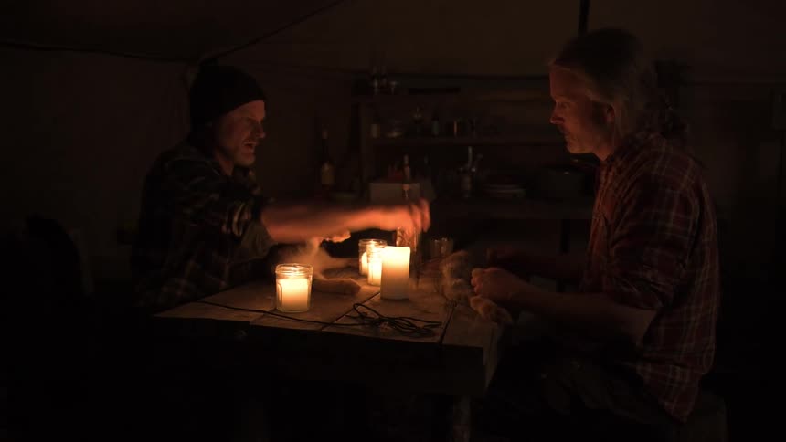 Hunters are skinning rabbits by candle light