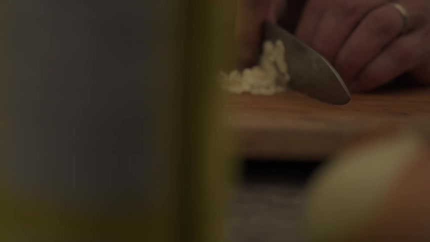 A person is cutting a garlic clove in their kitchen