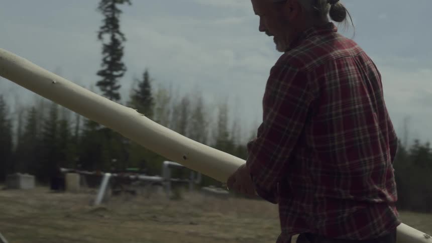A man lifts a log and leans it on a stand