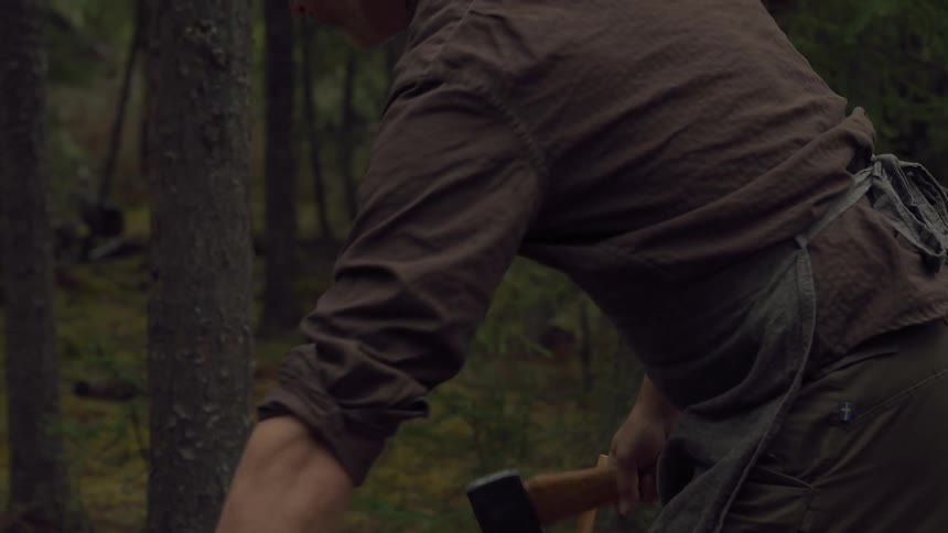 A man cuts kindling in the woods